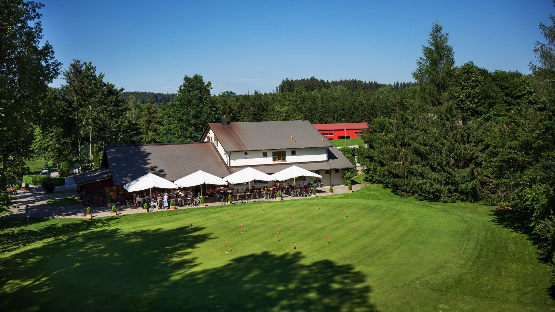Aufnahme des Clubhauses mit Restaurant des Allgäuer Golf- und Landclub e.V. inkl. Putting Green im Vordergrund