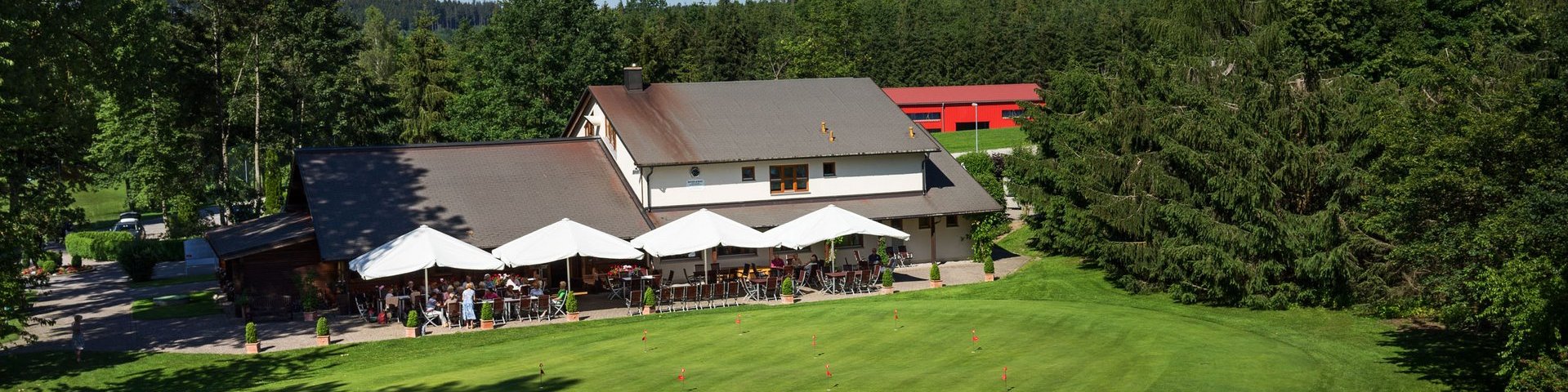 Aufnahme des Clubhauses mit Restaurant des Allgäuer Golf- und Landclub e.V. inkl. Putting Green im Vordergrund