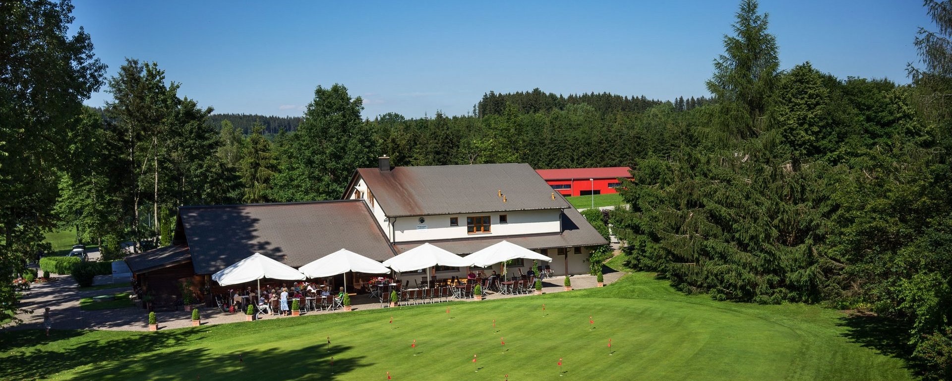 Aufnahme des Clubhauses mit Restaurant des Allgäuer Golf- und Landclub e.V. inkl. Putting Green im Vordergrund