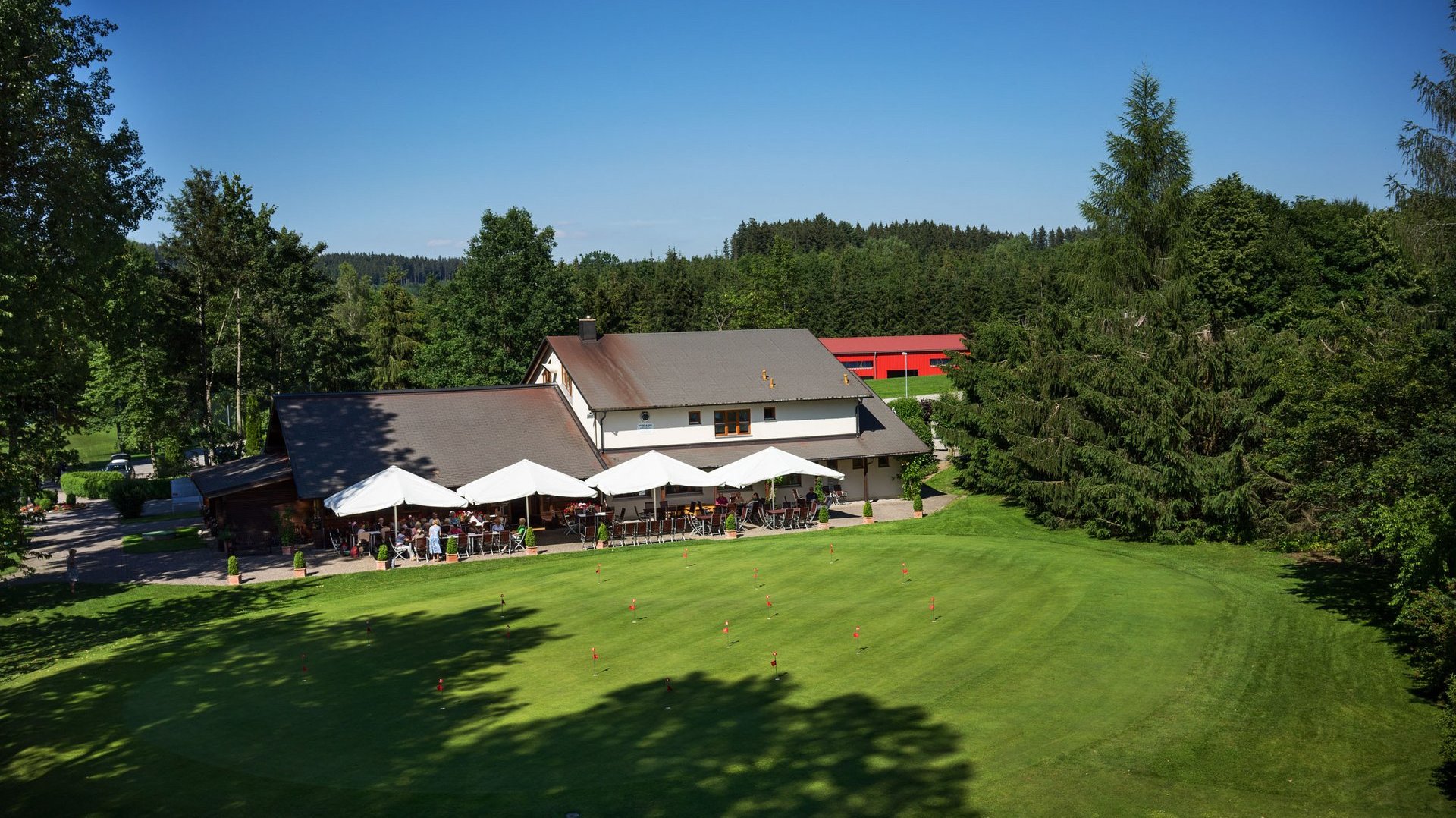 Aufnahme des Clubhauses mit Restaurant des Allgäuer Golf- und Landclub e.V. inkl. Putting Green im Vordergrund