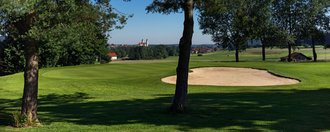 Das Grün mit Bunkern der Golfbahn 04 auf der Golfanlage Allgäuer Golf- und Landclub e.V. Ottobeuren mit der Basilika im Hintergrund