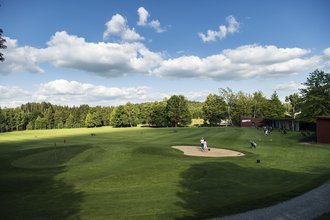 Die Driving-Range des Allgäuer Golf- und Landclub e.V. mit vielen Golfern in den Schlaghäuschen und vielen auf dem Green verteilten Golfbällen