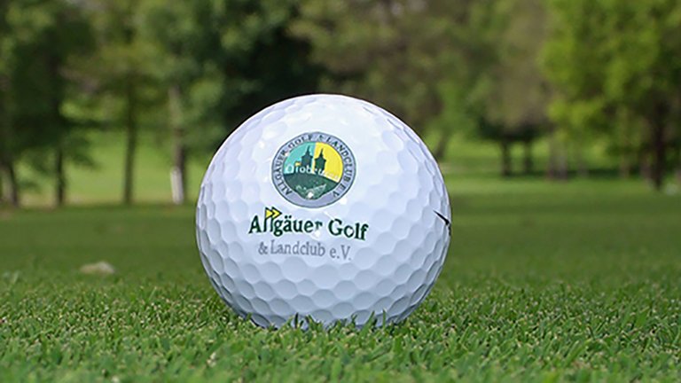 Detailansicht eines Golfballs mit dem Logo des Allgäuer Golf- und Landclub e.V.  auf dem Green liegend